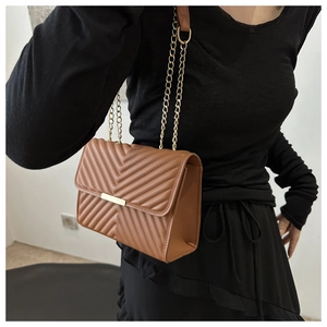 Brown chevron quilted shoulder bag with gold chain strap shown on a model outfit