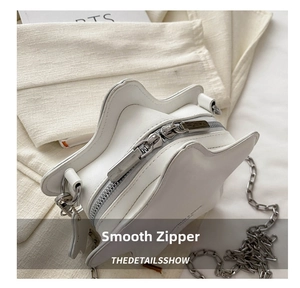 Detail of smooth silver double zippers and texture on white star-shaped crossbody bag