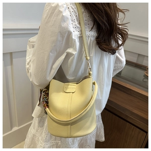 Schicke gelbe Eimer-Tasche aus Leder mit Seidentuch am Griff, getragen am Modell