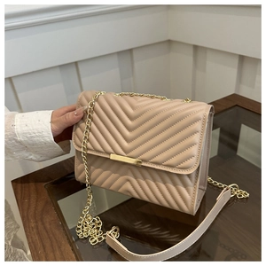 Macro detail of beige V-quilted chain bag showing gold metal hardware and PU leather texture