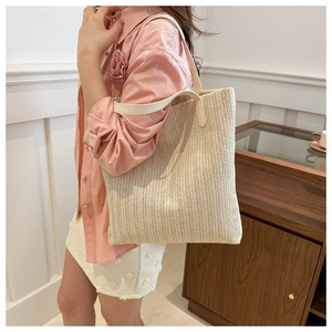 Detail of handwoven straw tote bag featuring creamy V-shape texture and white leather strap