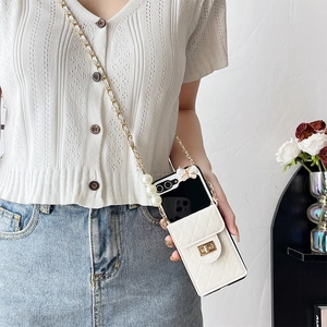 Detail of white quilted leather phone case with pearl chain and butterfly ornament