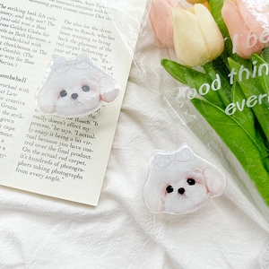Detail of two white puppy phone grips with blue bows on a soft white fabric background
