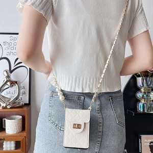 White quilted mini crossbody phone bag with pearl chain strap worn by a model