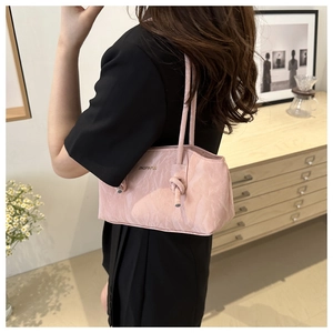 Vue détaillée du sac à main plissé rose avec logo doré porté à l'épaule par un mannequin