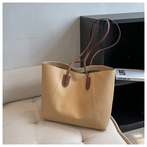 Detail view of large beige tote bag with slim brown shoulder straps on a cozy bench