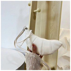 Detailed view of the white quilted croissant bag featuring knotted handle and zip closure