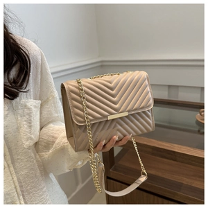 Detail of V-quilted stitching and gold metal buckle on beige leather crossbody bag