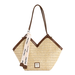 Large straw tote bag with brown leather handles and decorative white logo ribbon