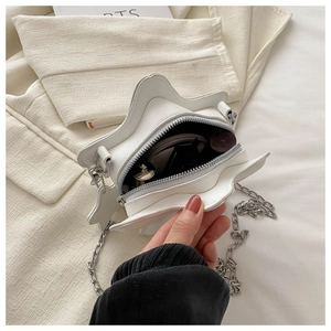 Macro shot of white star-shaped bag with silver chain and lipstick inside the open compartment