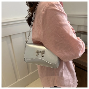 Silver underarm bag featuring a prominent metal butterfly bow and sleek chain strap