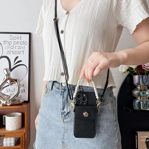 Crossbody phone case with black quilted leather, pearl handle, and gold flower detail