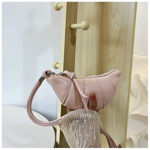Detail of pink croissant-shaped mini pouch with vertical pleated stitching and strap