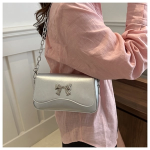 Detail of silver metallic square bag with bow clasp and thin metal chain strap