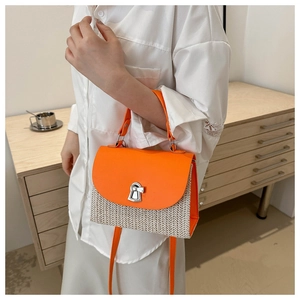 Detail of a woven straw crossbody bag with orange leather flap and silver twist lock