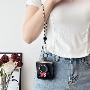 Detail of camera-style leather case with a polka dot bow and houndstooth lanyard