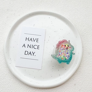Close-up of cute dinosaur phone grip with colorful star sequins and glitter gradient
