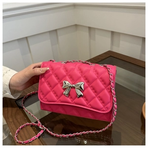 Detail of rose pink quilted crossbody bag with silver bow accent and chain strap