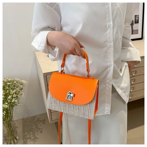 Detail of orange flap straw handbag with silver keyhole lock and braided texture