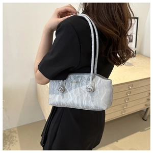 Sac sous le bras plissé argenté avec texture métallique porté par un mannequin en studio