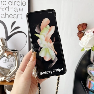 Detail of Galaxy Z Flip4 case featuring large pearls and black gold metal chain strap
