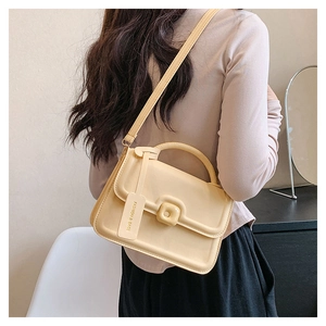 Detailed back view of a beige leather crossbody handbag worn by a model in soft lighting
