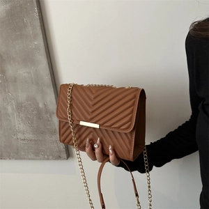 Brown chevron quilted crossbody bag with gold chain strap and metallic bar detail