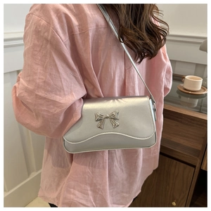 Silver leather crossbody bag with metal butterfly detail and wavy edge on a model