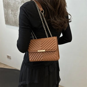 Brown leather crossbody chain bag with V-shaped quilting shown on model back