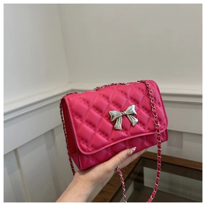 Close-up of fuchsia quilted bag with silver chain strap and decorative bow clasp