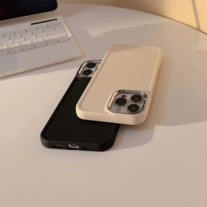Close-up of matte silicone phone cases with silver metal camera frames on a desk