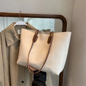 Minimalist cream white tote bag with brown straps shown in a natural lifestyle setting