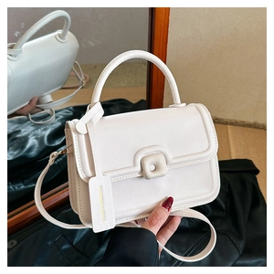 Detail of white PU leather crossbody bag with decorative round buckle and side tag