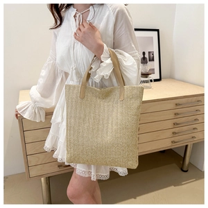 Detailed view of handmade woven straw tote bag with brown faux leather handles