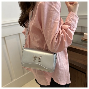 Silver crossbody bag detail featuring metallic butterfly buckle and elegant chain strap