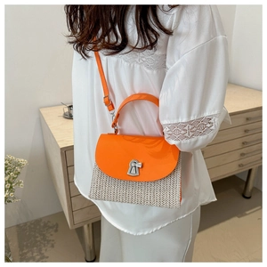 Detail of a woven straw crossbody bag with orange leather trim and a gold twist lock clasp