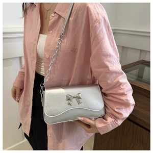Detail of silver flap crossbody bag featuring metallic bow buckle and chain strap