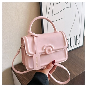 Pink leather handbag detail showing padded edges, square buckle, and brand tag