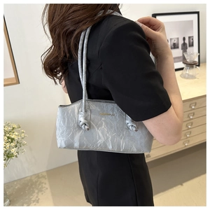 Détails de la texture plissée argentée et de la bandoulière nouée du sac à bandoulière