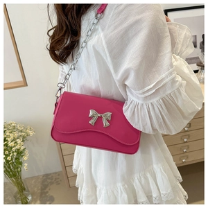 Close-up of rose pink crossbody bag with silver butterfly buckle on white dress