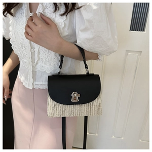 Detail of woven straw handbag with black smooth flap and golden twist lock closure