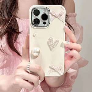 Cream iPhone case with pink bows and pearl heart charm held by a person in pink attire