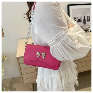 Detail of rose red shoulder bag with silver butterfly buckle and chain strap on a model