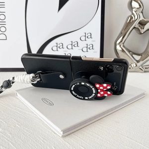 Detail of Galaxy Z Flip case with camera stand, Minnie bow and woven strap on white book