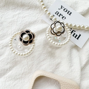 Close-up of camellia flower phone grips with pearls and star sequins on a textured surface