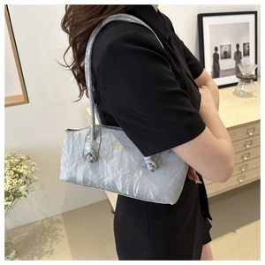 Détail d'un sac à bandoulière gris argenté à texture froissée avec logo doré élégant