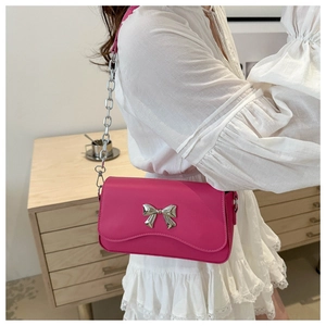 Detail of rose red crossbody bag featuring silver butterfly buckle and chain strap