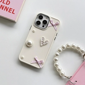Detail of cream iPhone case with pink gingham bows, pearls, and a textured silver heart charm