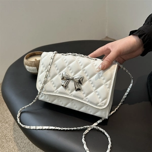 Quilted white chain crossbody bag with a silver metal bow accent and elegant PU leather