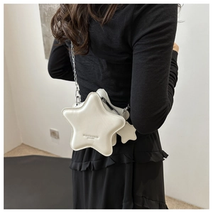 Star-shaped cream crossbody bag with silver chain worn on back over black attire